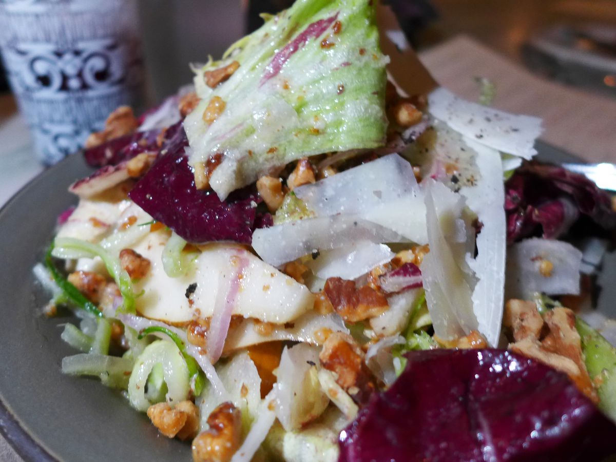 A pile of glistening lettuce, beets, and nuts.