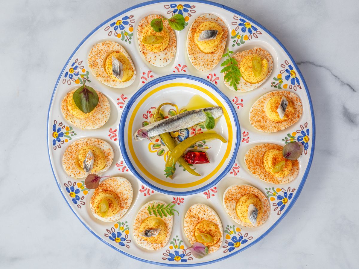 A plate with deviled eggs with sardines in the middle.