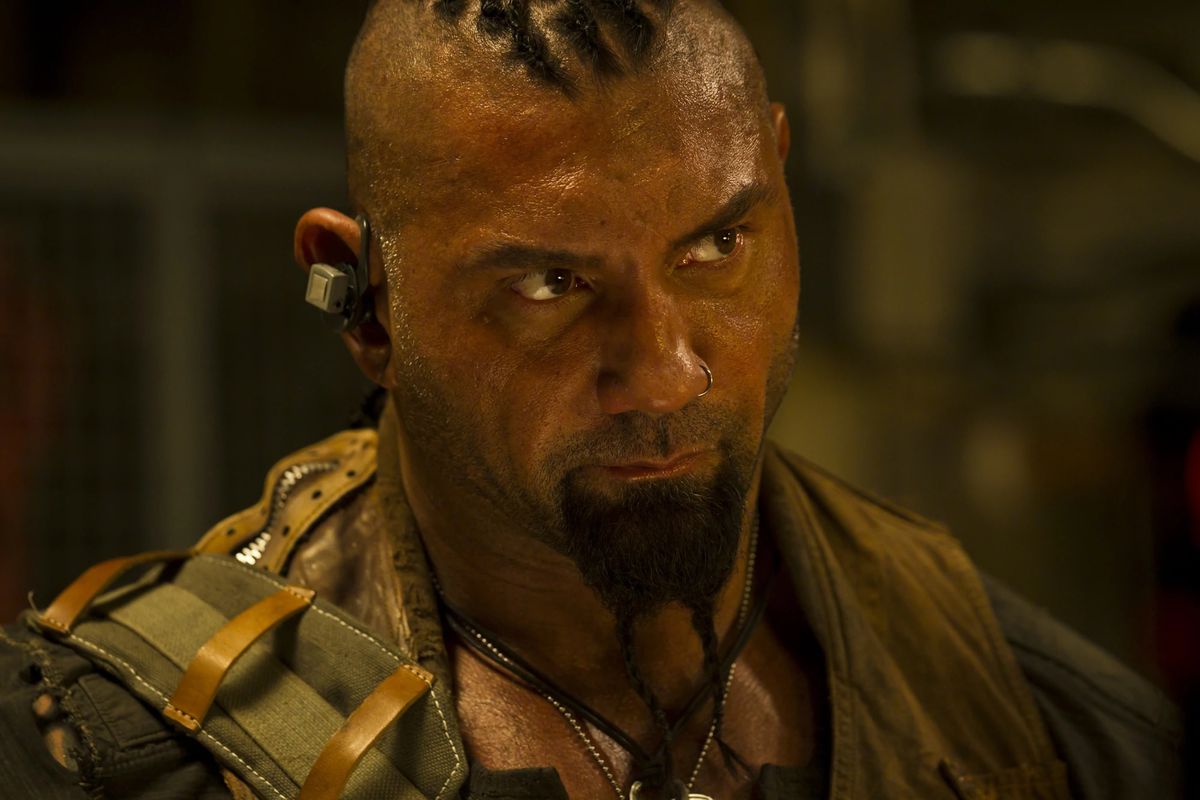 Dave Bautista is shiny with sweat in a military uniform in Riddick.