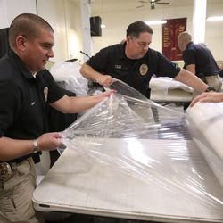 Utah Transit Authority police officers Bryan Kono and Todd Hewitt help unwrap 150 donated Leesa mattresses at the Rescue Mission of Salt Lake on World Homeless Day in Salt Lake City on Wednesday, Oct. 10, 2018.