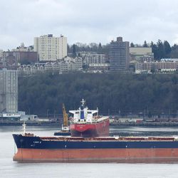 Two ships sit anchored in Commencement Bay near the Port of Tacoma's grain facility, left, Friday, Feb. 20, 2015, in Tacoma, Wash. With a Friday deadline looming, negotiators for the two sides in the contract dispute that has snarled international trade at U.S. West Coast seaports are laboring to reach a settlement as billions of dollars of cargo are sitting massive ocean-going ships anchored outside port facilities. 