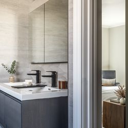 The primary bath, adjacent to the homeowners’ bedroom, features a wall-hung double vanity with white- quartz countertops and sleek black faucets. 