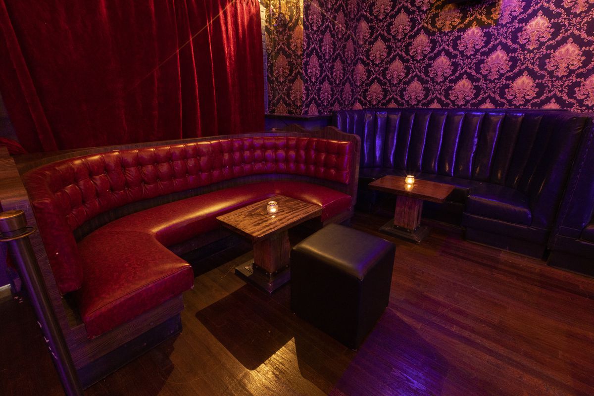 A red leather booth inside a speakeasy-style bar.