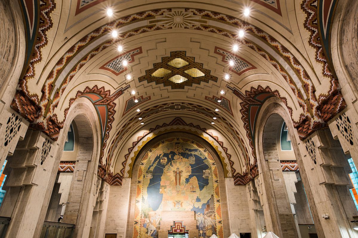 The interior of the Guardian Building. The ceiling is arched and painted with an elaborate design. The walls are arched and there is a large mural on the far wall.