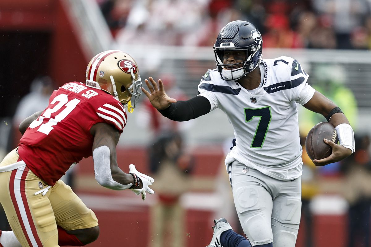 Geno Smith #7 of the Seattle Seahawks attempts to stiff arm Tashaun Gipson Sr. #31 of the San Francisco 49ers as he runs with the ball during an NFL football game between the San Francisco 49ers and the Seattle Seahawks at Levi’s Stadium on January 14, 2023 in Santa Clara, California.