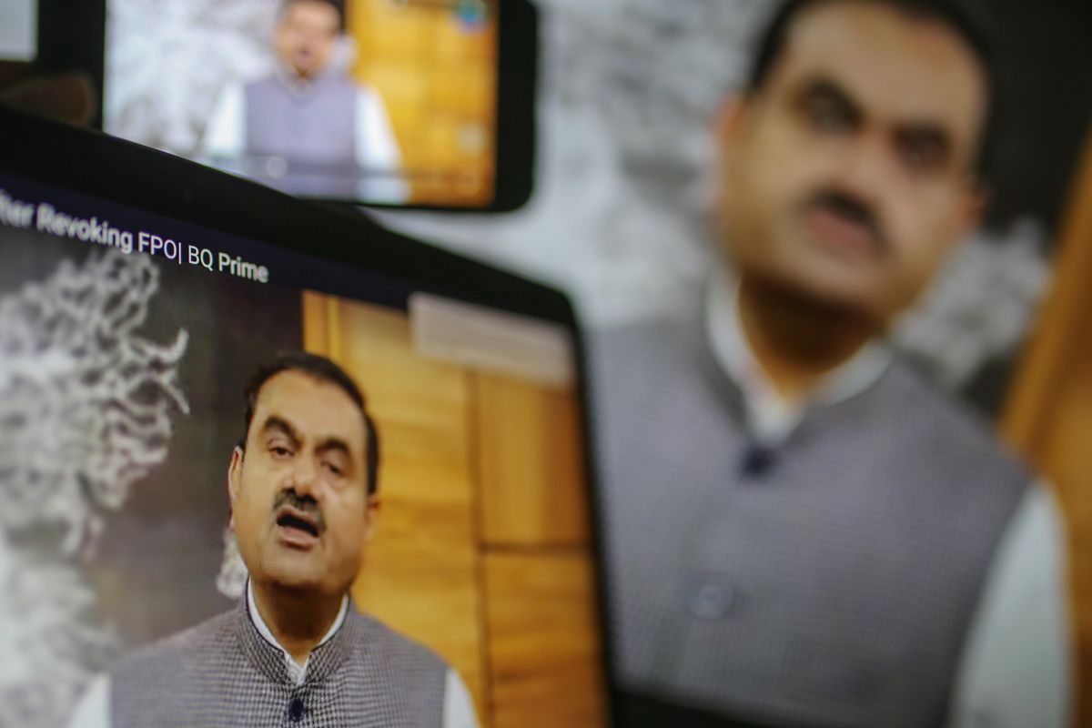 Adani speaking to a camera, shown on several screens.