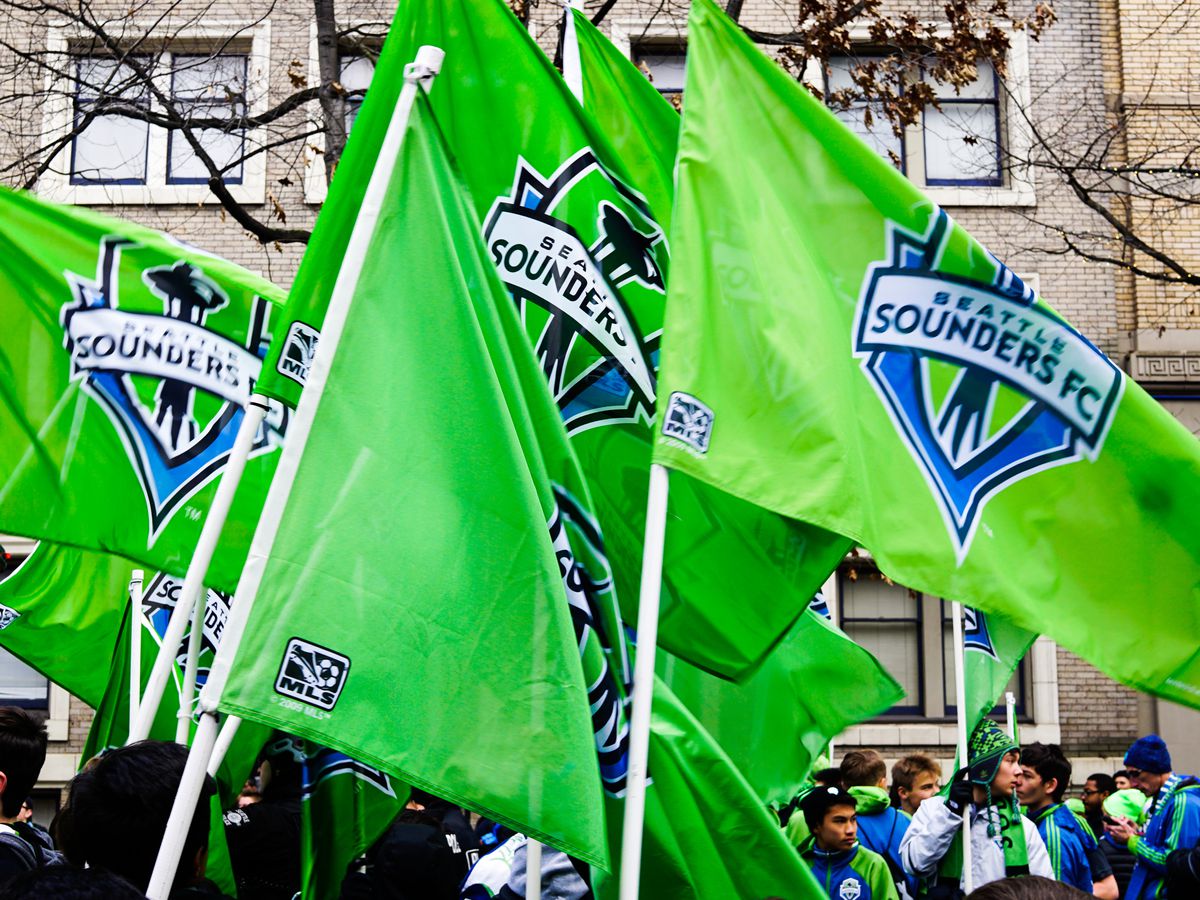 A collection of bright green Seattle Sounders flags, displaying the team’s logo prominently.