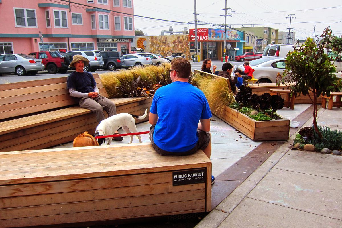 People sitting in a mini park on a San Francisco sidewalk, with dogs.