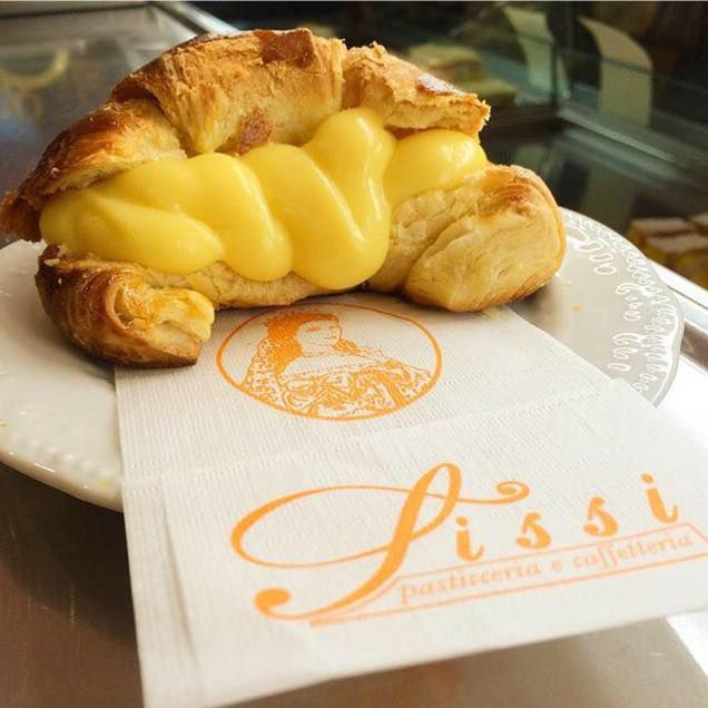 A yellow cream-stuffed croissant on a branded napkin