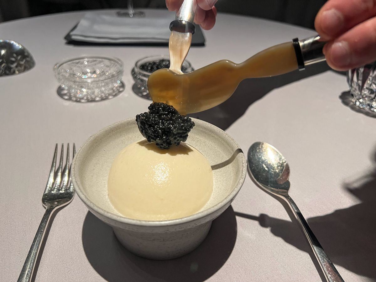 A server dollops caviar onto a dome of egg cream. 