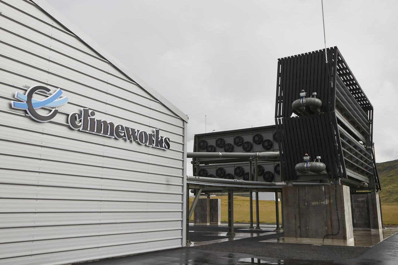 A building that says “Climeworks” next to equipment that looks like shipping containers filled with fans.