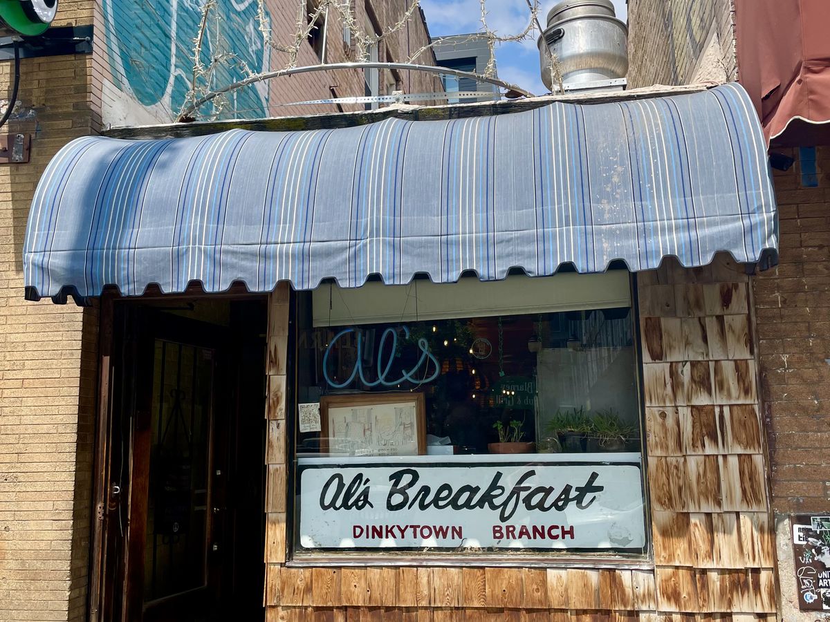 A small restaurant with a blue awning and a sign in the window that reads “Al’s Breakfast.”