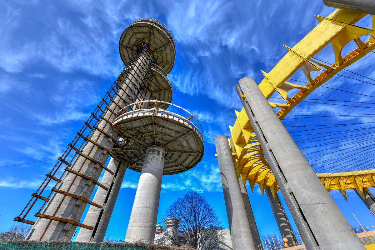 Three tall towers and a smaller round one painted in yellow rise above Flushing Meadows-Corona Park. 