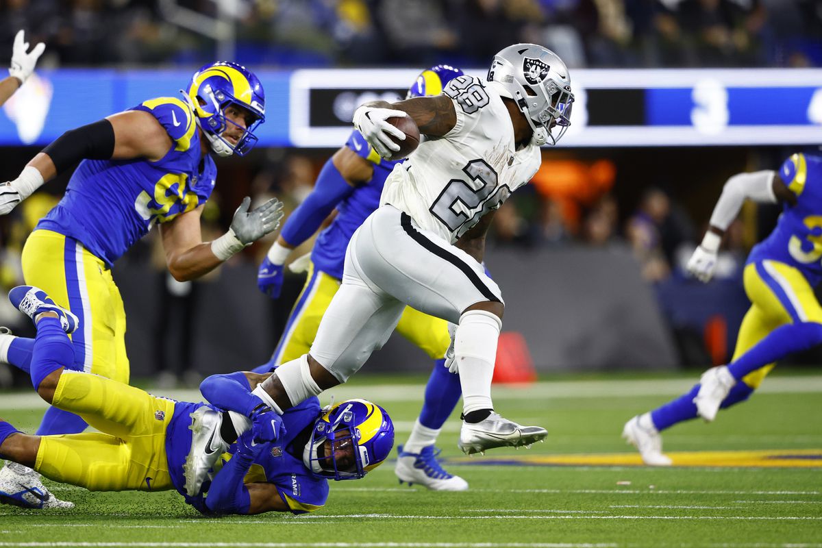Josh Jacobs #28 of the Las Vegas Raiders carries the ball as Cobie Durant #14 of the Los Angeles Rams attempts a tackle during the second quarter at SoFi Stadium on December 08, 2022 in Inglewood, California.