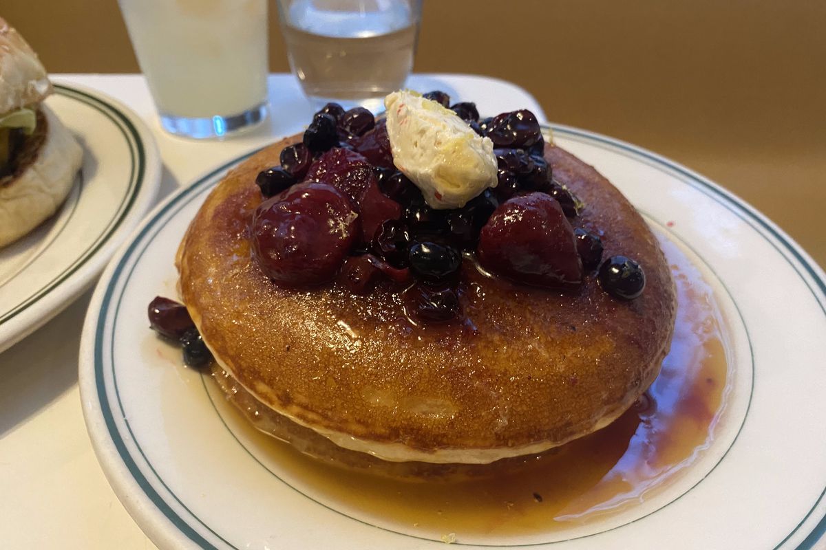 A stack of two pancakes with a pile of butter and berries.