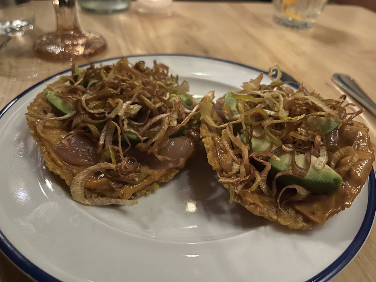 Two tuna tostadas topped with crispy leeks.