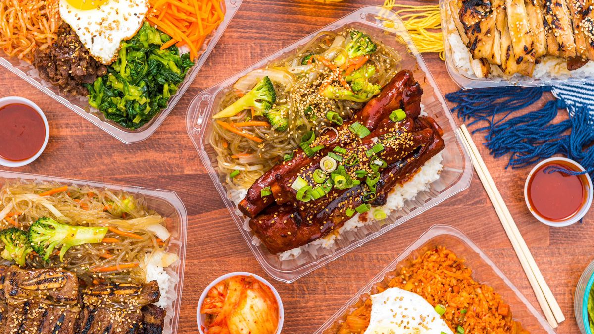 A spread of takeout Korean barbecue in clear plastic takeout containers