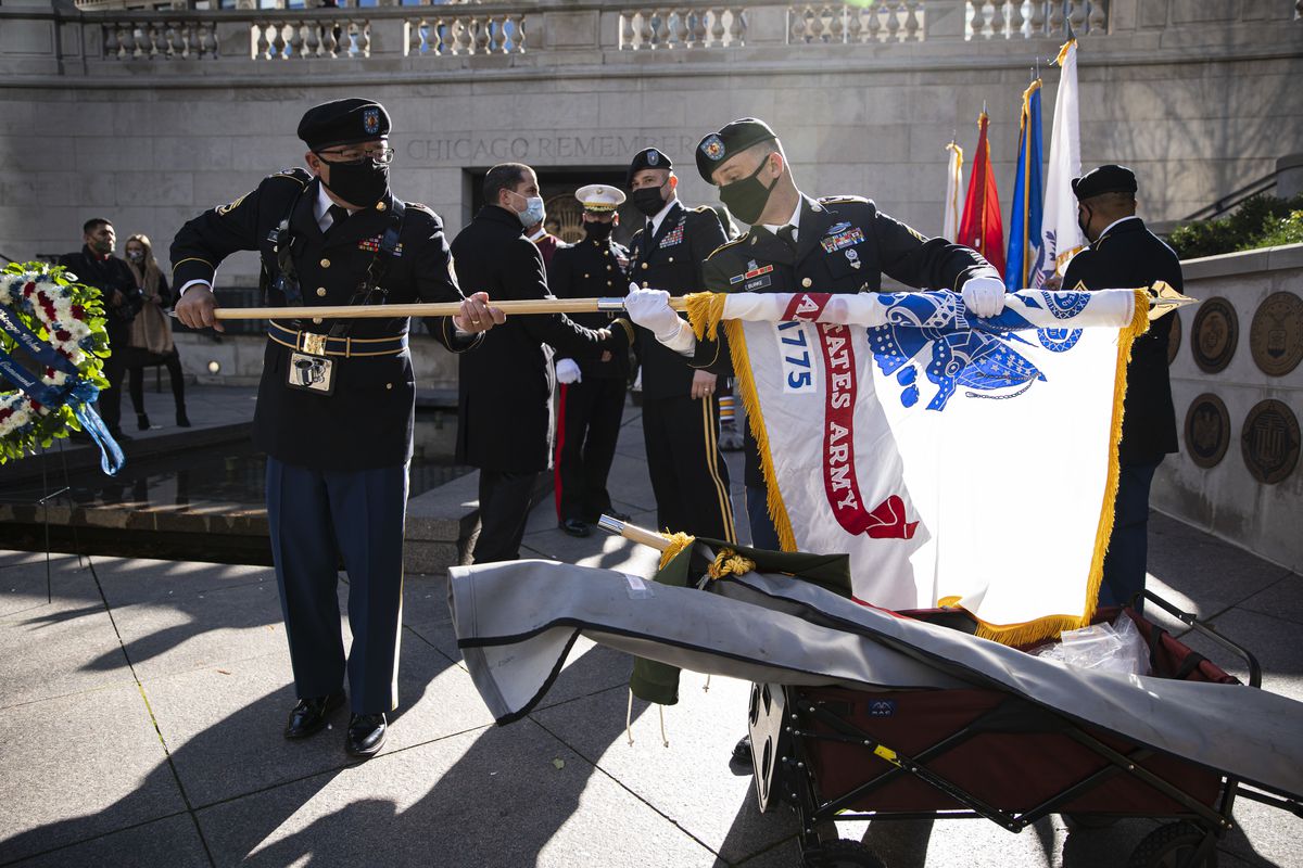Members of an Army color guard unfurl a U.S. Army Flag during a ceremony on the Chicago Riverwalk in the Loop, Wednesday, Nov. 11, 2020.