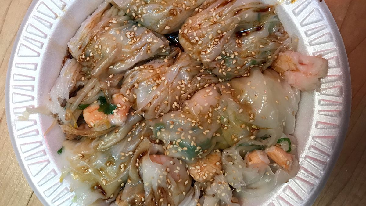 A white styrofoam plate with rice noodle and shrimp rolls