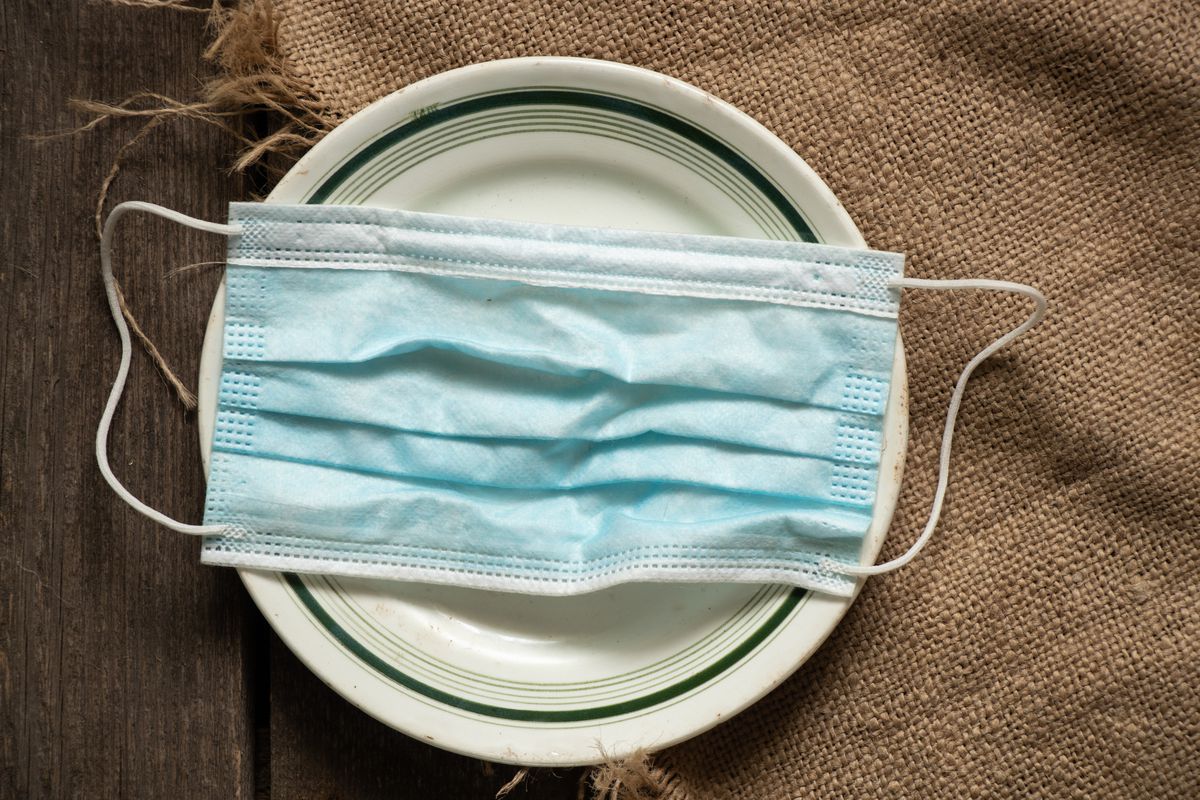 A light blue face covering on a white plate with a burlap cloth underneath.