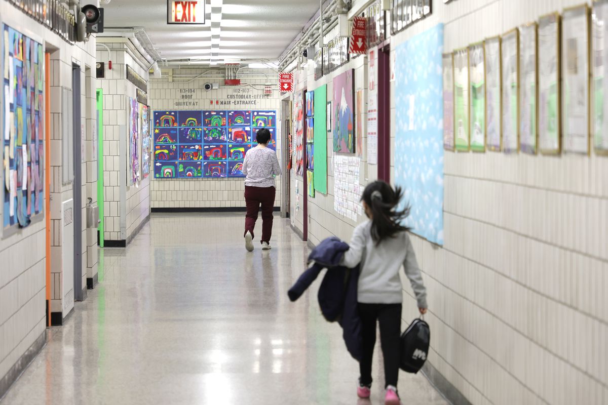 A photo of a school hallway, where the principal is walking, followed by a child. 