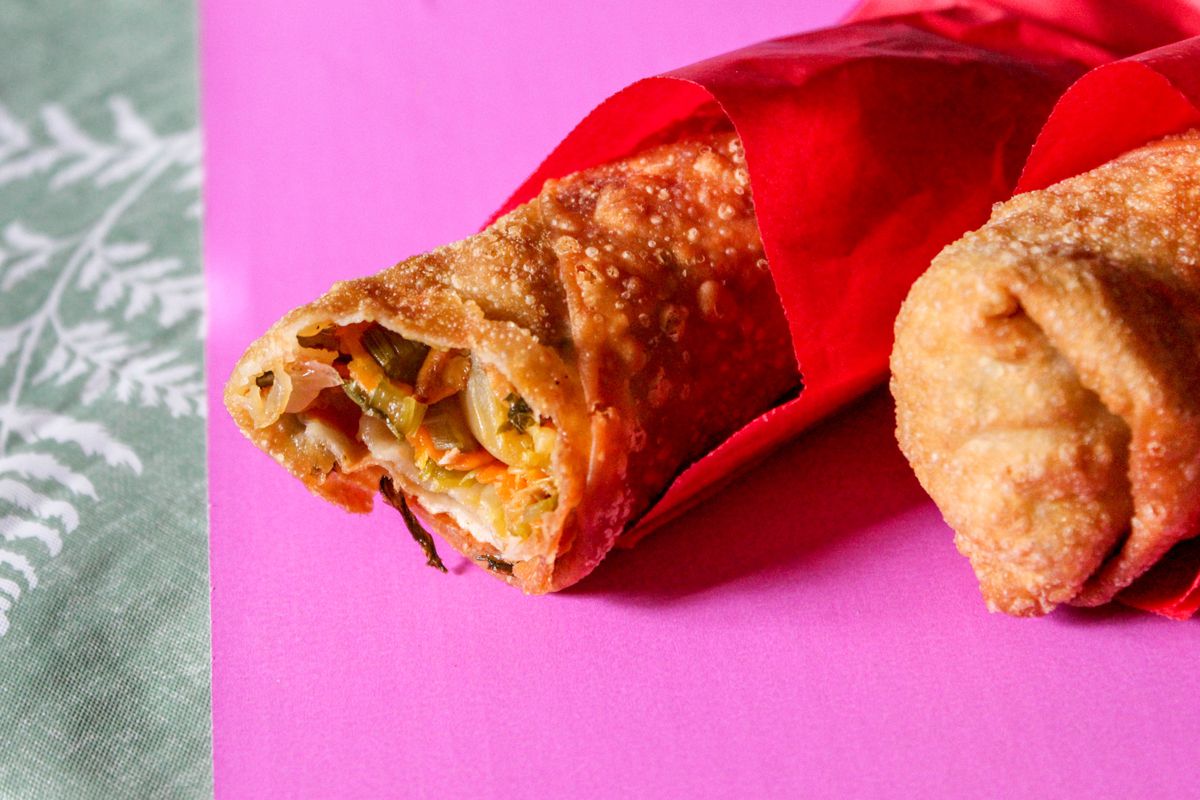 A close up of two egg rolls in red wrappers.