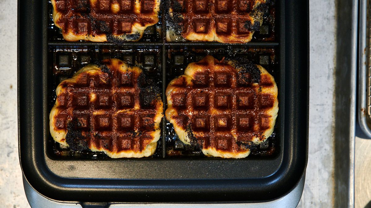 Four babka waffles sit in the waffle press at Ava Gene’s. The sugar on the outside of them has created a caramelized brown on them, with patches of black from the poppyseeds