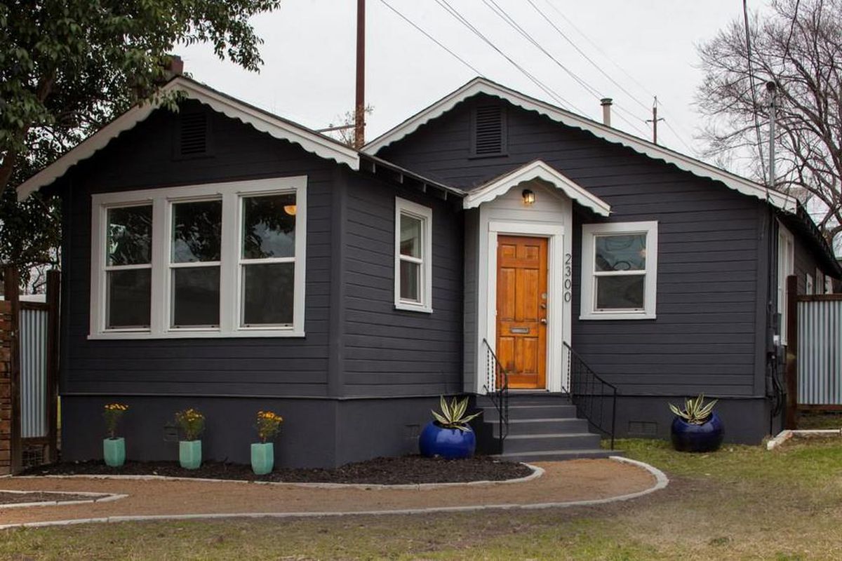 Dark gray 1940s wood house with white trim, orange door