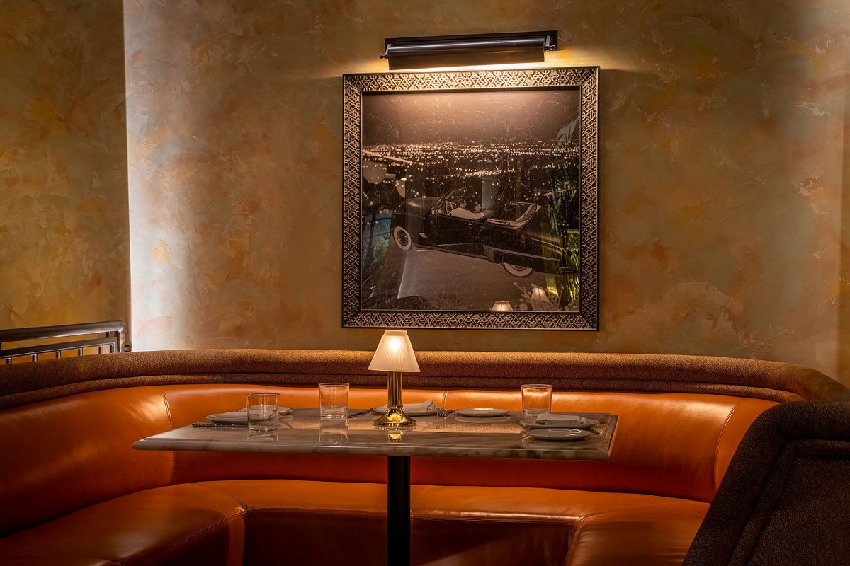 A wide leather booth with marble table and old hollywood images at a new restaurant.