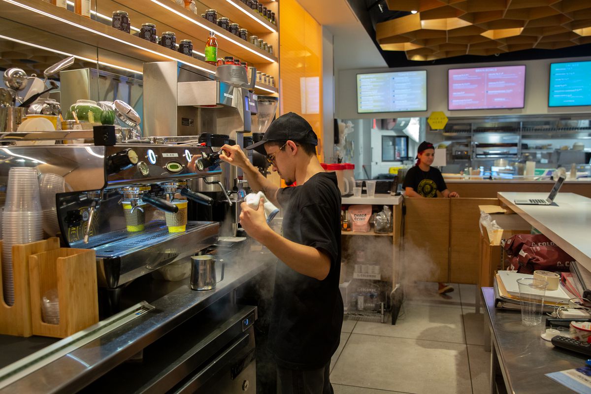 Honeybrains worker Jan Santos makes a latte at the chain’s Flatiron location, July 15, 2021.