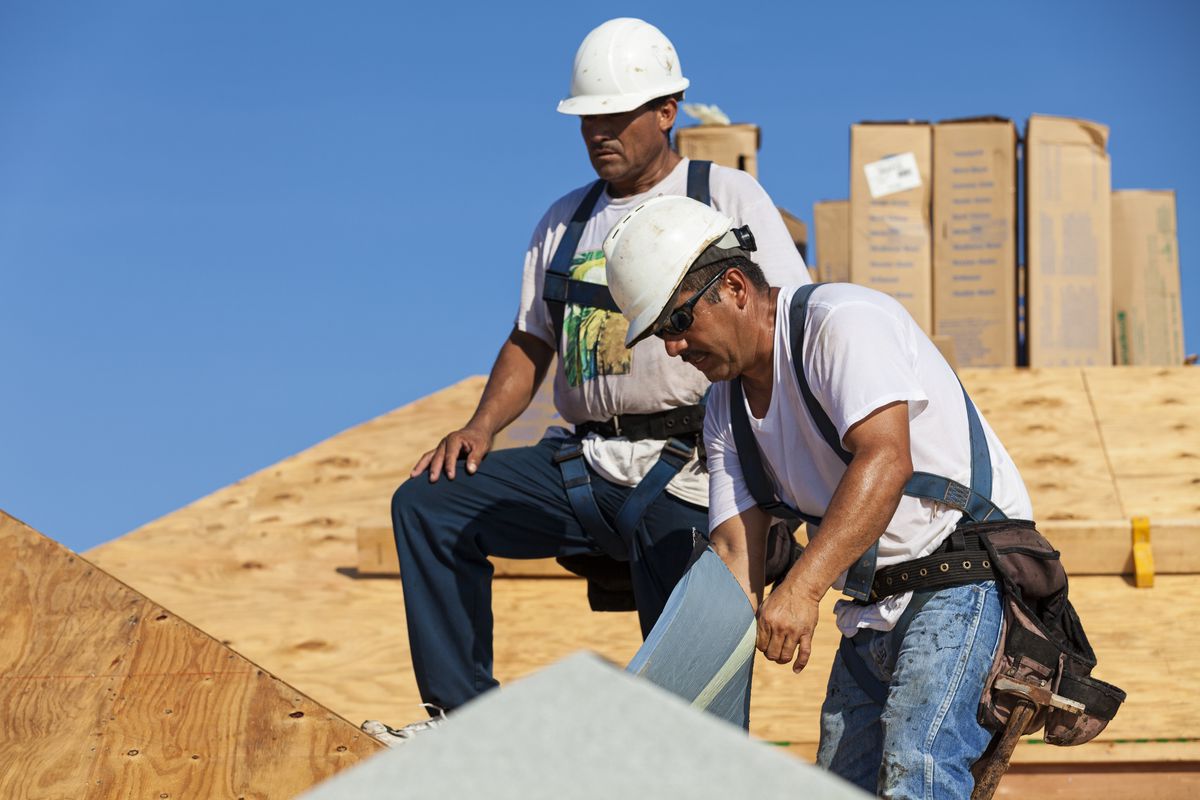 Two Latino workers on a roof.