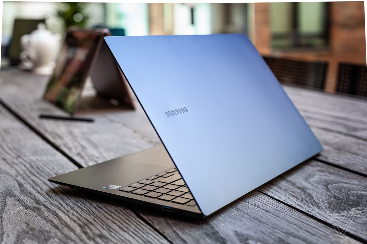 The Samsung Galaxy Book Pro half open, angled away from the camera slightly to the right on a picnic table.