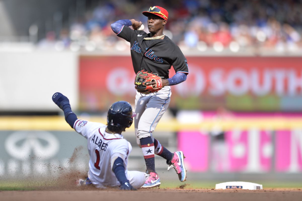 Jazz Chrisholm Jr. #2 of the Miami Marlins throws to first base as Ozzie Albies #1 of the Atlanta Braves slides into second base in the fifth inning against the Miami Marlins at Truist Park