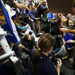 Fans crash onto the floor after a railing gives way while trying to get autographs from Golden State Warriors guard Stephen Curry, right, before an NBA regular season game against the Utah Jazz at the Vivint Arena in Salt Lake City, Wednesday, March 30, 2016.