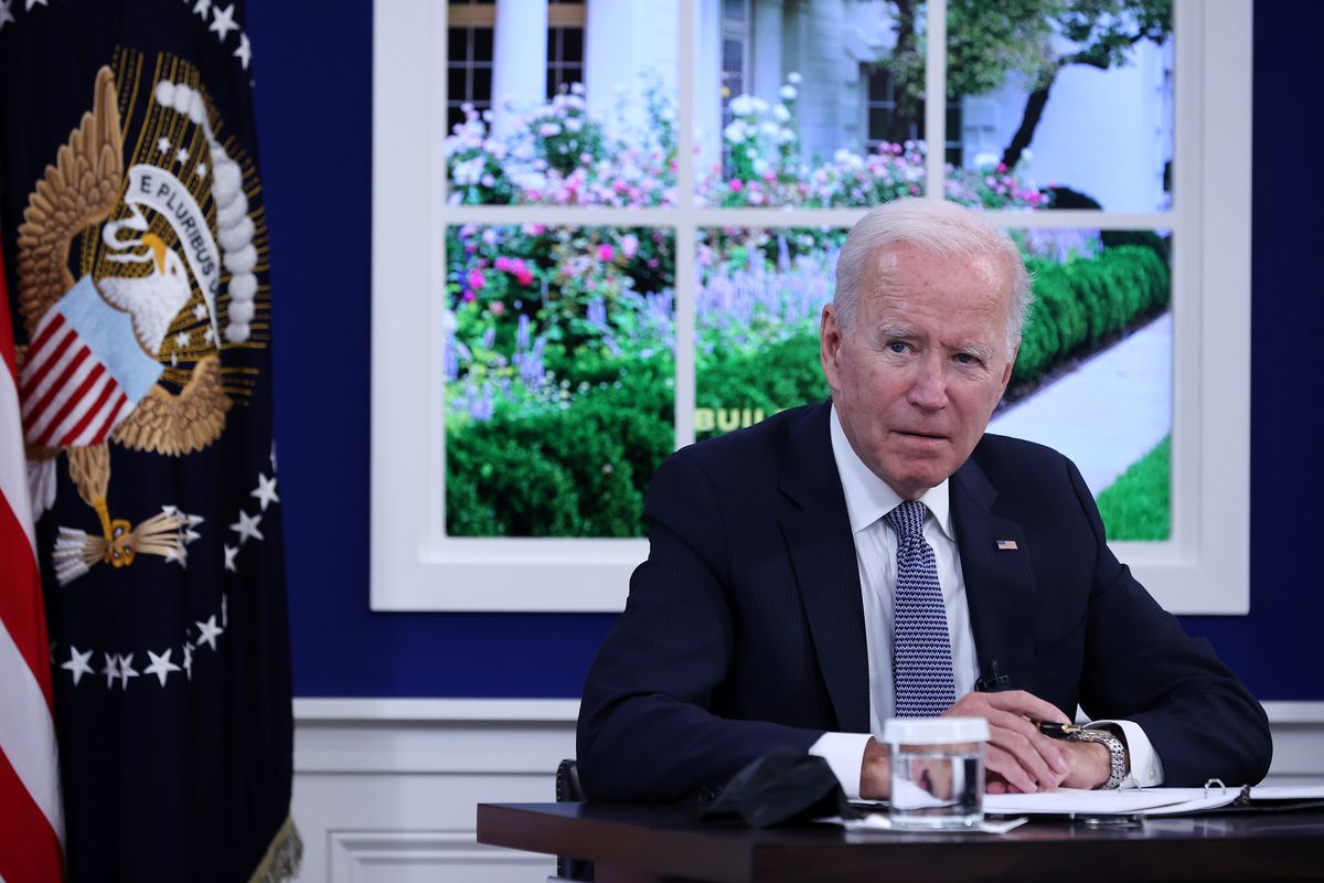President Joe Biden sitting at a conference table with a window behind him.