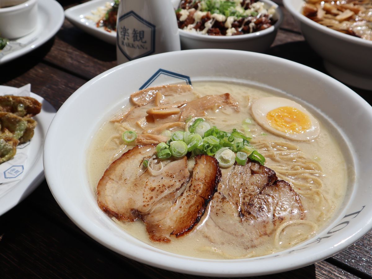 A creamy bowl of ramen topped with char siu, green onion, mushrooms, and a halved egg.