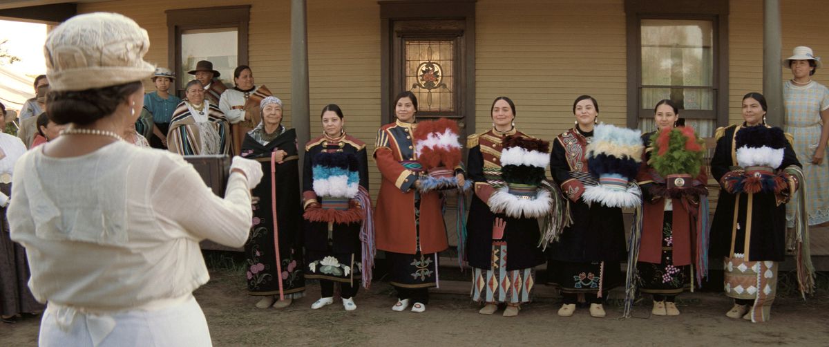 Mollie (Lily Gladstone), in formal traditional Osage dress, stands with a group of other dressed-up Native women, posing for a picture in Killers of the Flower Moon