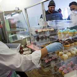 Leslie Fiet, owner of Mini's Gourmet Cupcakes, arranges cupcakes as Steve Monroe and Nate Purvis shop at the store in Salt Lake City on Friday, Feb. 6, 2015. Purvis had driven past the cupcake shop frequently in the past but was motivated to stop there today after hearing of Fiet's heroic deeds. Fiet rescued a kidnapped 3-year-old girl on Wednesday evening.