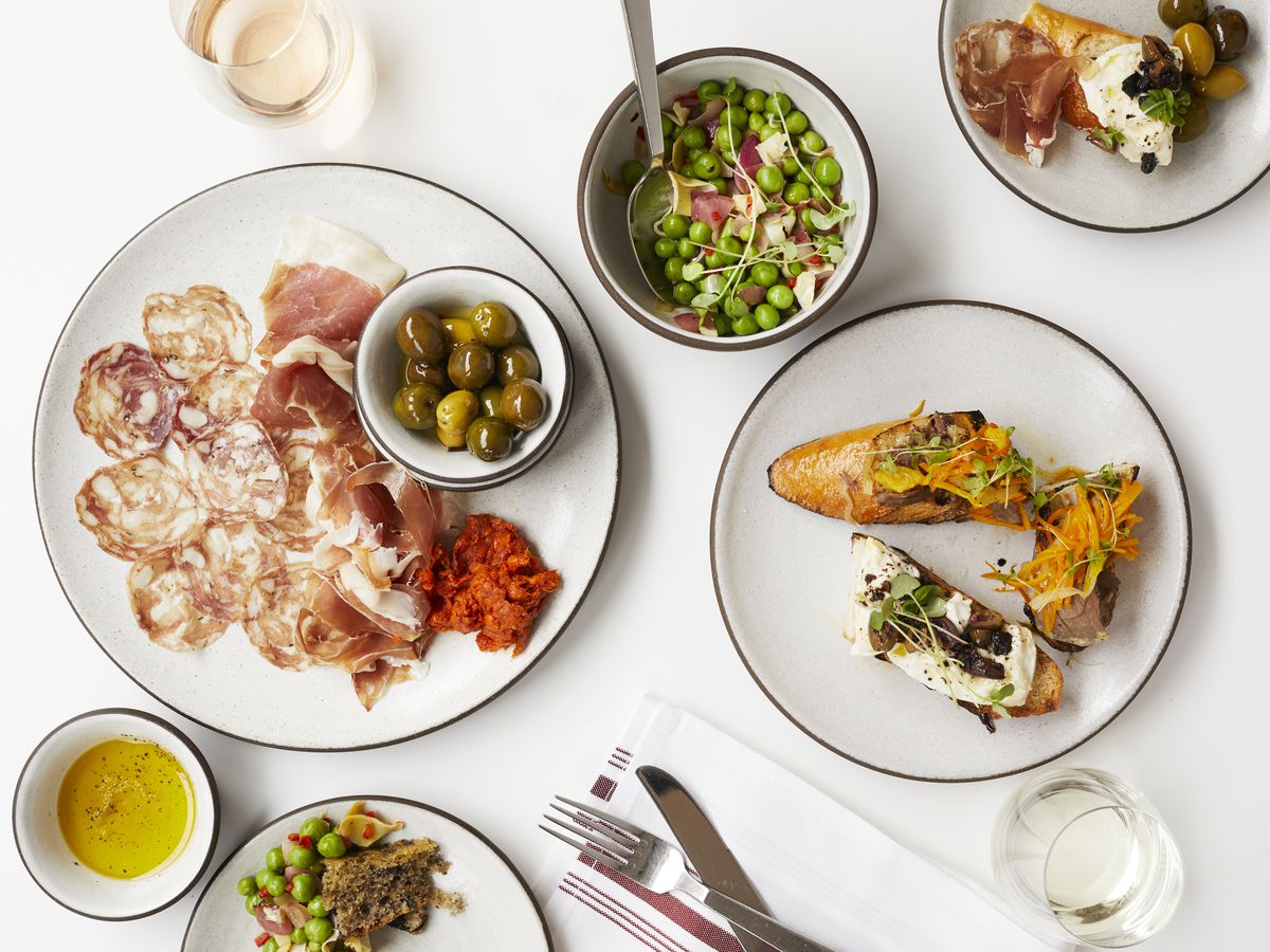A spread of Italian dishes — including salumi, olives, and more — on a bright white surface