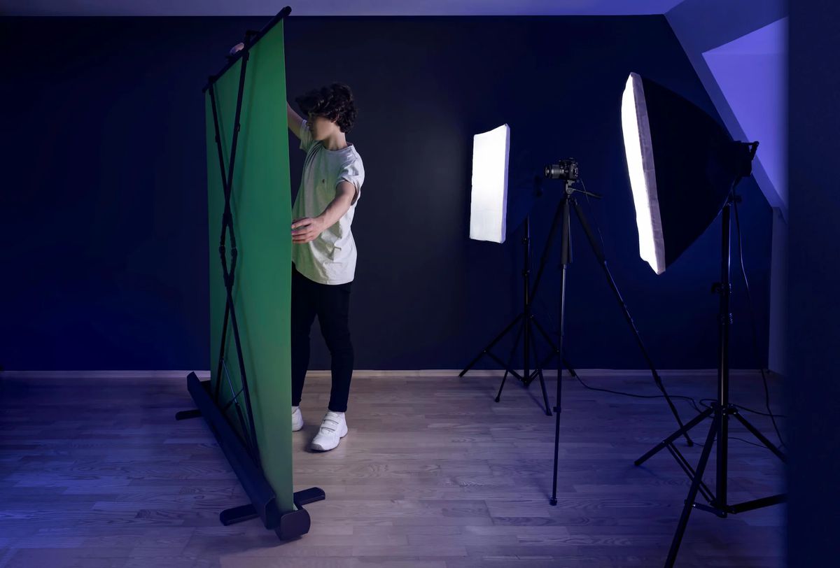 A photo that’s showing someone setting up Elgato’s Green Screen in a room with two large key lights shining directly on it.