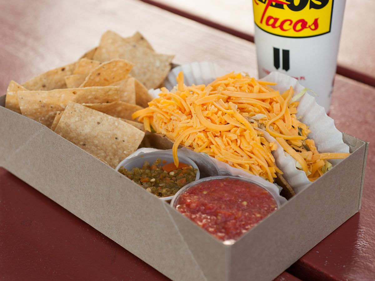 A box of tacos from Tito’s, with shredded cheese on top of hard shells.