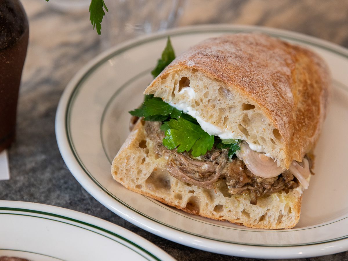 A sandwich filled with stewed beef on a ciabatta bun. 