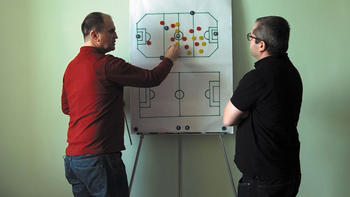 The subject of Infinite Football explains its proposed rules to the director.