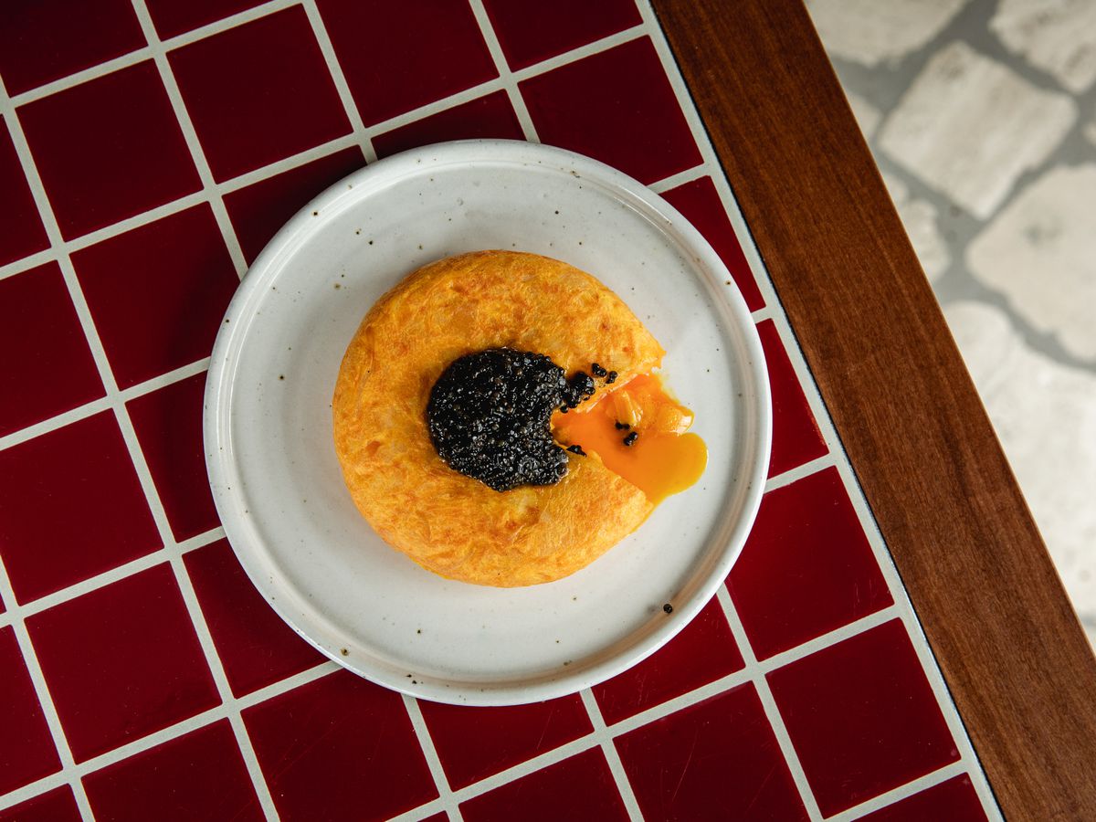 Spanish potato tortilla with caviar, on a red tile background at Decimo restaurant at The Standard London