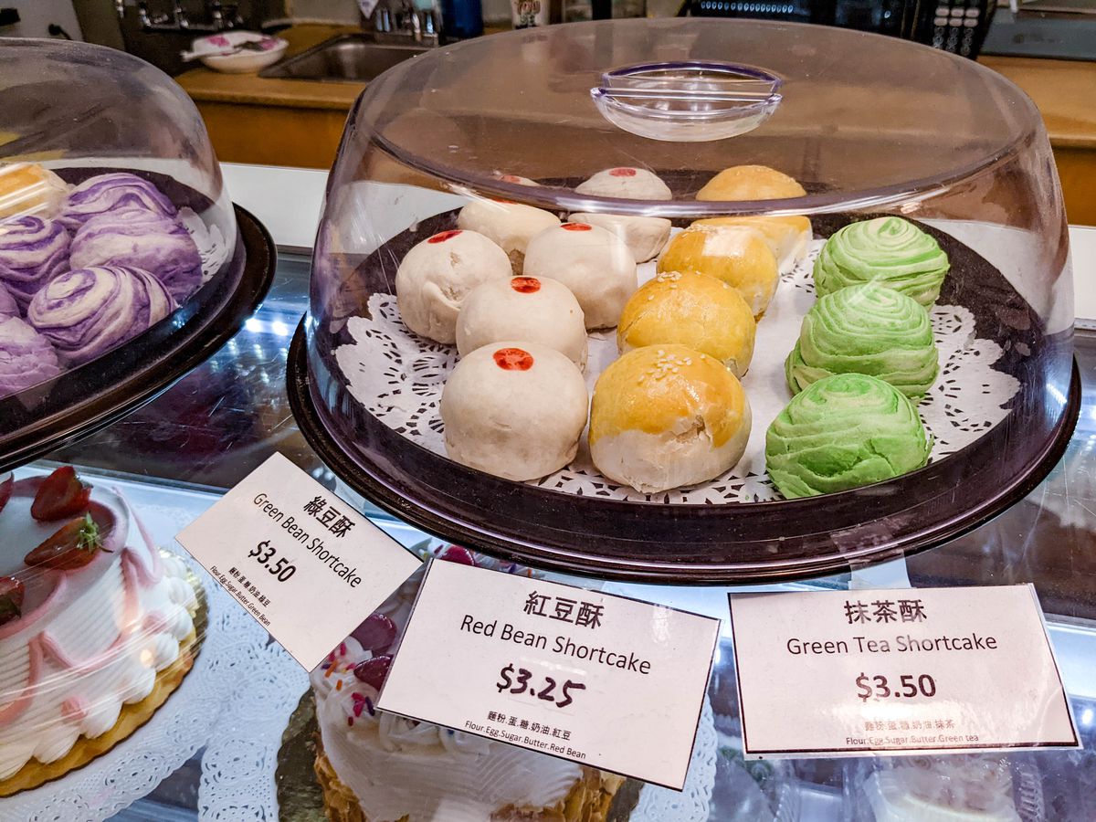 Small, round Chinese mooncakes are on display in a small glass case, including several varieties —&nbsp;green bean, red bean, and green tea, labelled as shortcakes.