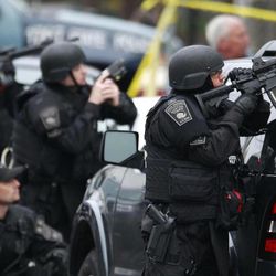 Police in tactical gear surround an apartment building while looking for a suspect in the Boston Marathon bombings in Watertown, Mass., Friday, April 19, 2013. All residents of Boston were ordered to stay in their homes Friday morning as the search for the surviving suspect in the marathon bombings continued after a long night of violence that left another suspect dead. 