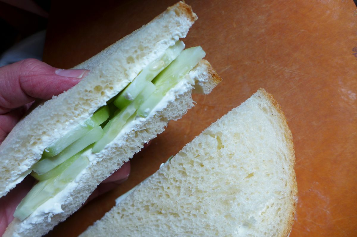 White bread sandwich with sliced cucumbers, both sides smeared with white soft cheese.