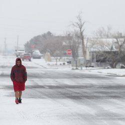 A man walks on Milbury Avenue, Friday, Feb. 27, 2015, in Odessa, Texas. A Texas snowstorm has closed schools, snarled traffic and forced a main highway to Oklahoma to shut down after dozens of vehicles slipped off the road.