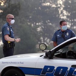 Colorado Springs police officers wear masks for smoke as they man a roadblock to an evacuated area of forest, ranches and residences, in the Black Forest wildfire area, north of Colorado Springs, Colo., on Thursday, June 13, 2013.  The blaze in the Black Forest area northeast of Colorado Springs is now the most destructive in Colorado history, surpassing last year's Waldo Canyon fire, which burned 347 homes, killed two people and led to $353 million in insurance claims. (AP Photo/Brennan Linsley)
