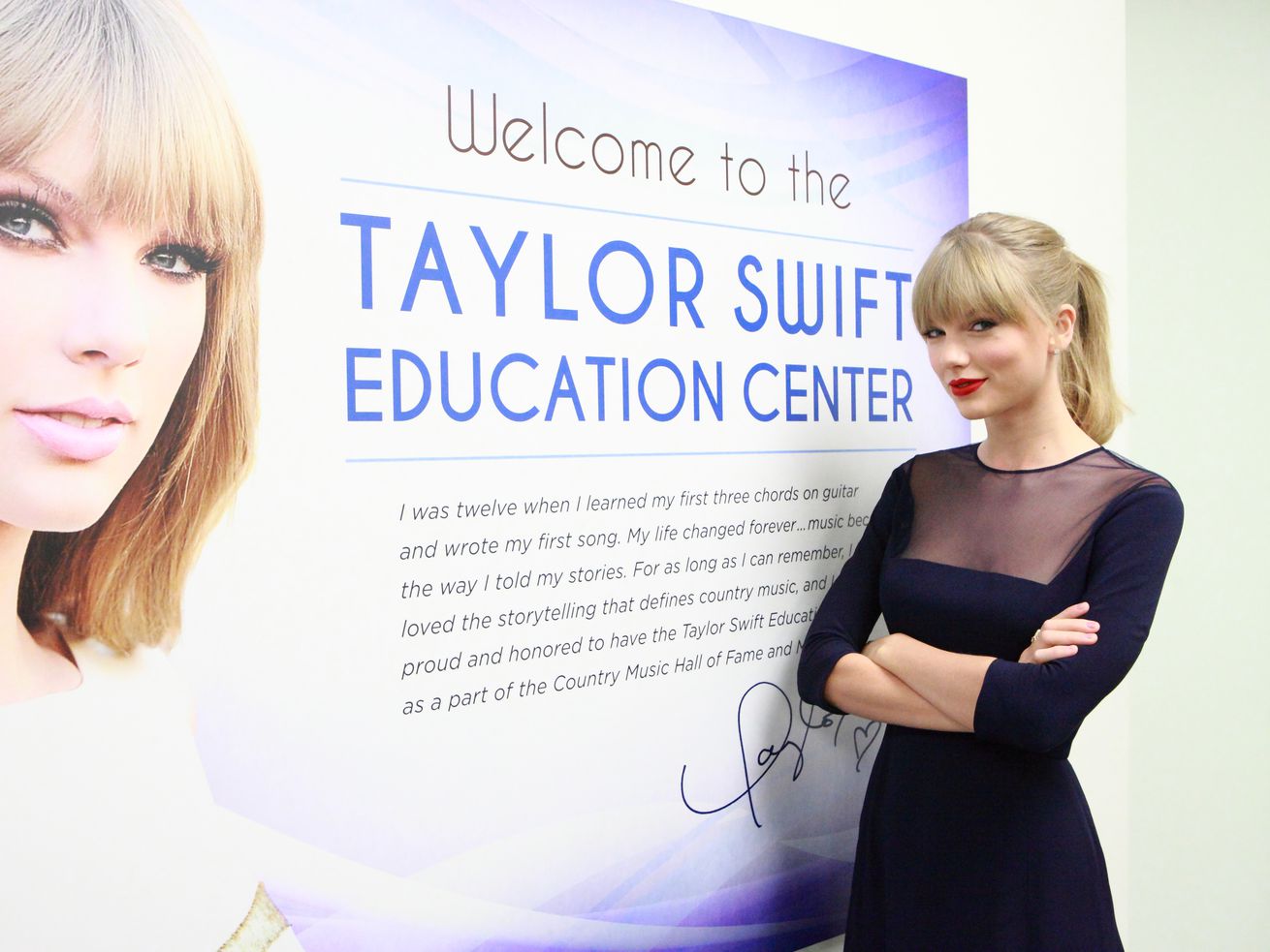 Taylor Swift in front of a sign for the Taylor Swift Education Center